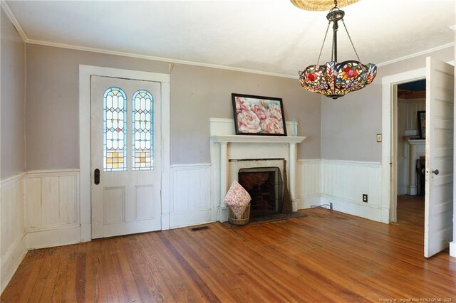 5648 Tolarsville Rd, Saint Pauls, NC 28384 - foyer featuring a fireplace, wood finished floors, a wainscoted wall, crown molding, and a chandelier