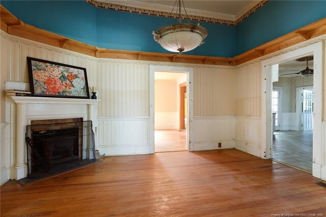 5648 Tolarsville Rd, Saint Pauls, NC 28384 - unfurnished living room with wood-type flooring, ceiling fan, wainscoting, a fireplace with flush hearth, and wallpapered walls