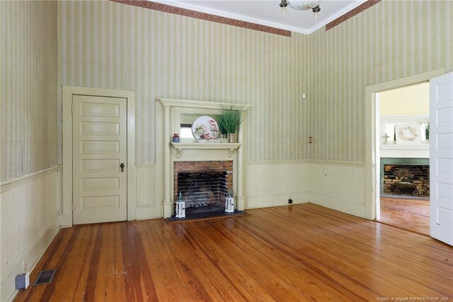 5648 Tolarsville Rd, Saint Pauls, NC 28384 - unfurnished living room with a fireplace, wood-type flooring, wallpapered walls, a wainscoted wall, and crown molding