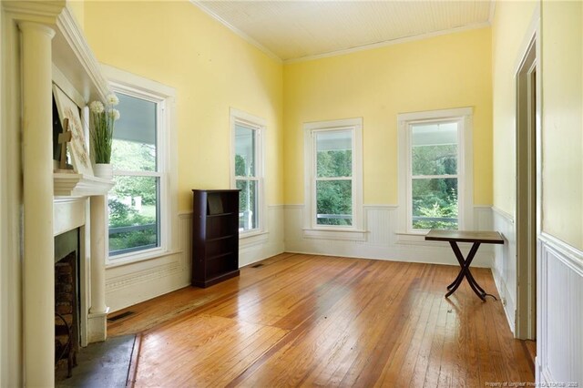 5648 Tolarsville Rd, Saint Pauls, NC 28384 - spare room with hardwood / wood-style floors, a wainscoted wall, crown molding, and a fireplace