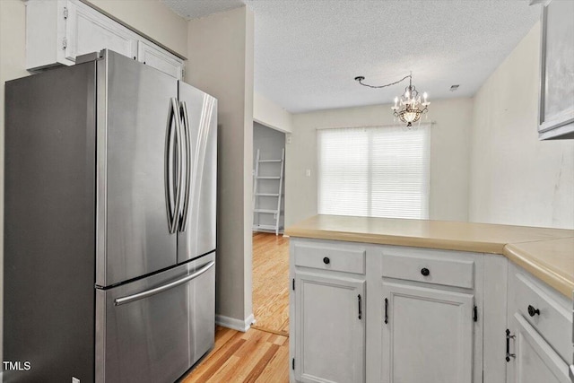 4705 Walden Pond Dr Unit 110-C, Raleigh, NC 27604 - kitchen with freestanding refrigerator, light wood-type flooring, a peninsula, a textured ceiling, and white cabinetry