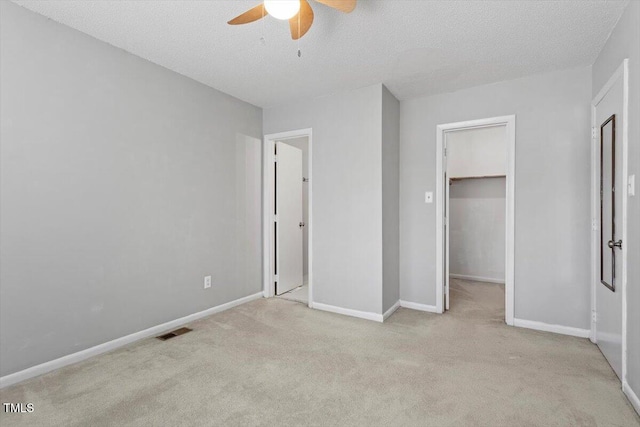4705 Walden Pond Dr Unit 110-C, Raleigh, NC 27604 - unfurnished bedroom featuring a walk in closet, carpet flooring, baseboards, a ceiling fan, and a textured ceiling