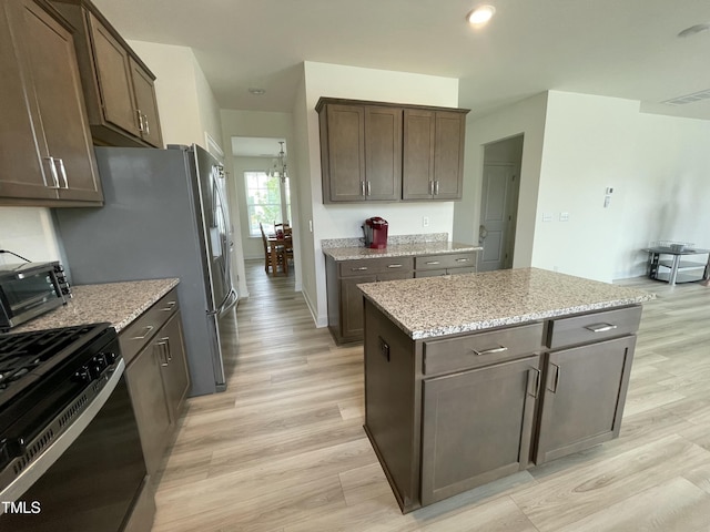 30 Junius Birch Trl, Franklinton, NC 27525 - kitchen with stainless steel range with gas stovetop, light wood finished floors, dark brown cabinetry, and light stone counters