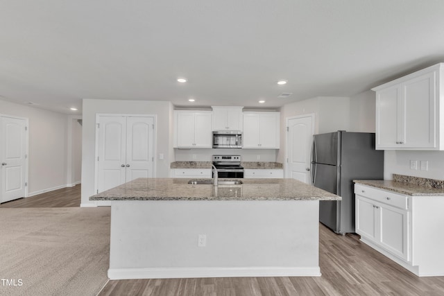 717 Little Patch St, Zebulon, NC 27597 - kitchen with stainless steel appliances, an island with sink, recessed lighting, light stone countertops, and white cabinetry