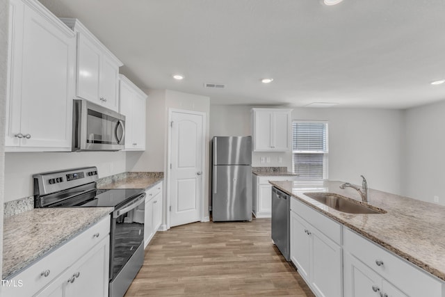 717 Little Patch St, Zebulon, NC 27597 - kitchen with stainless steel appliances, a sink, white cabinets, light wood-style floors, and recessed lighting