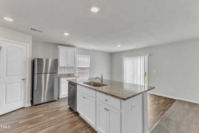 717 Little Patch St, Zebulon, NC 27597 - kitchen featuring stainless steel appliances, a sink, wood finished floors, stone counters, and white cabinets