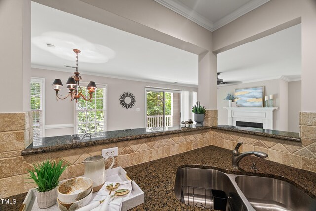 313 Glen Echo Ln Unit J, Cary, NC 27518 - kitchen featuring a sink, a chandelier, dark stone countertops, crown molding, and a fireplace