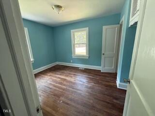 unfurnished bedroom featuring baseboards and dark wood-type flooring