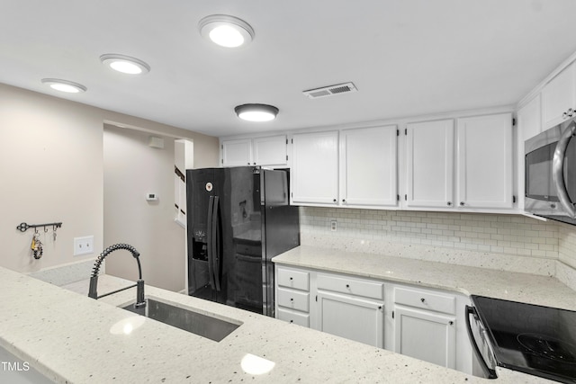2233 Alpine Rd, Durham, NC 27707 - kitchen with black refrigerator with ice dispenser, a sink, stainless steel microwave, light stone countertops, and white cabinetry