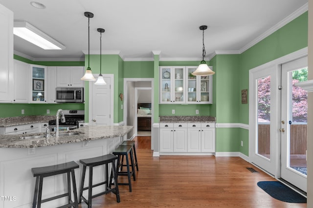 8536 Wolverton Fields Dr, Wake Forest, NC 27587 - kitchen with appliances with stainless steel finishes, a sink, white cabinetry, wood finished floors, and a breakfast bar