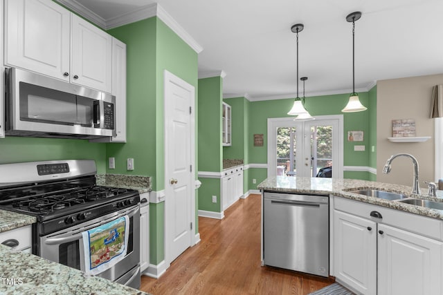8536 Wolverton Fields Dr, Wake Forest, NC 27587 - kitchen with stainless steel appliances, a sink, white cabinets, light wood finished floors, and ornamental molding
