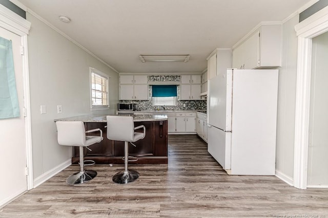 2911 Wicker St, Sanford, NC 27330 - kitchen featuring freestanding refrigerator, a peninsula, wood finished floors, and ornamental molding