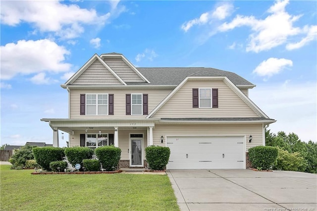 view of front of home with concrete driveway, a front yard, an attached garage, and a porch