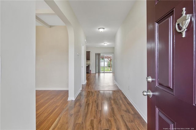 foyer entrance featuring wood finished floors, arched walkways, and baseboards