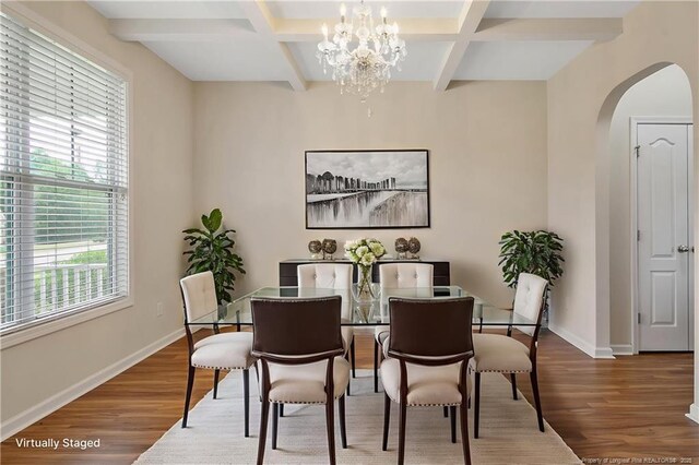 dining room featuring arched walkways, wood finished floors, coffered ceiling, beam ceiling, and baseboards