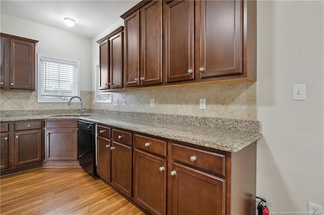 kitchen with a sink, dishwasher, tasteful backsplash, and light wood-style flooring