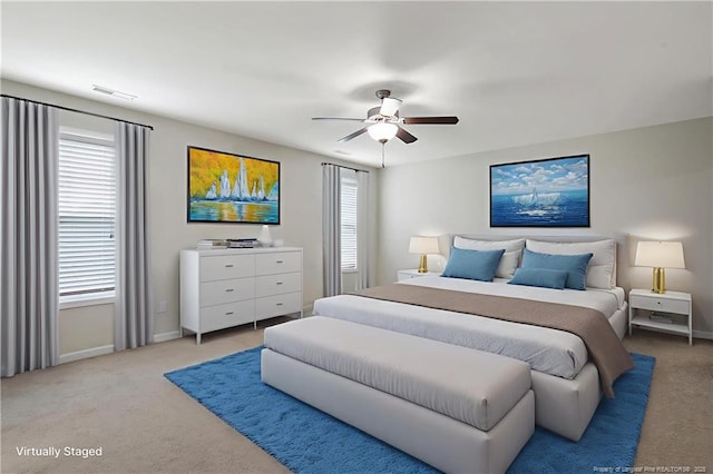 bedroom featuring light colored carpet, baseboards, and a ceiling fan