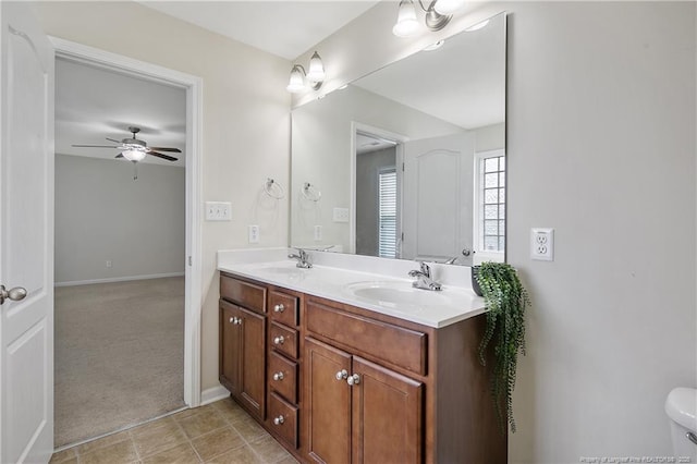bathroom with double vanity, ceiling fan, and baseboards