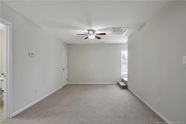 spare room with ceiling fan, light carpet, and baseboards