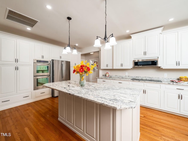 8917 Thompson Mill Rd, Wake Forest, NC 27587 - kitchen with appliances with stainless steel finishes, a center island, light wood-style floors, white cabinets, and hanging light fixtures
