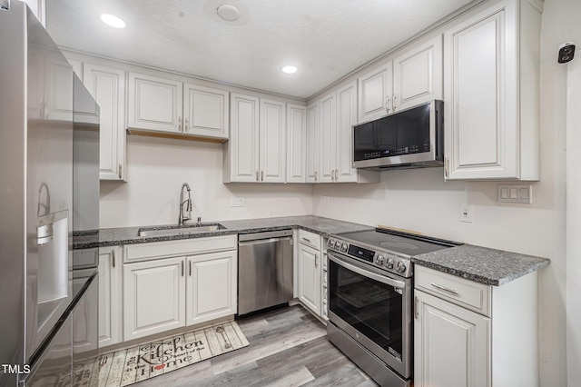 7368 Ryan St, Fayetteville, NC 28314 - kitchen featuring appliances with stainless steel finishes, a sink, white cabinets, dark stone countertops, and light wood-type flooring