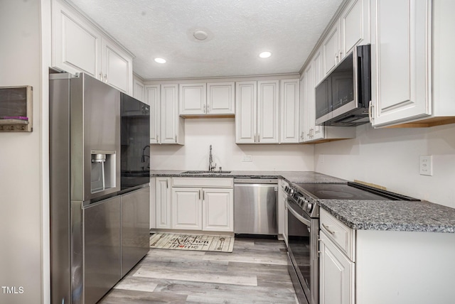 7368 Ryan St, Fayetteville, NC 28314 - kitchen featuring appliances with stainless steel finishes, a sink, recessed lighting, light wood-style flooring, and white cabinetry