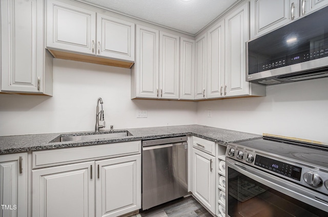 7368 Ryan St, Fayetteville, NC 28314 - kitchen featuring appliances with stainless steel finishes, a sink, white cabinets, and wood finished floors