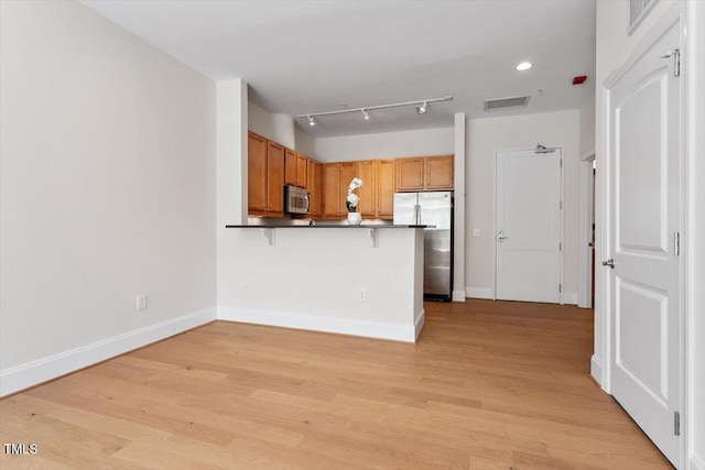 317 W Morgan St Unit 320, Raleigh, NC 27601 - kitchen featuring appliances with stainless steel finishes, dark countertops, a peninsula, a breakfast bar area, and baseboards