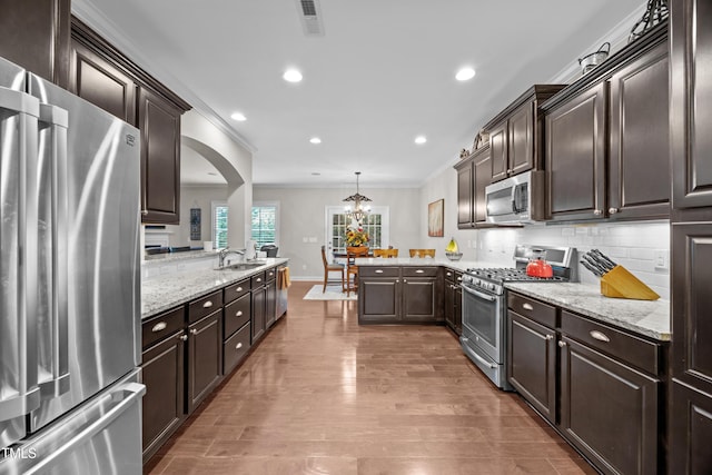 633 Copper Beech Ln, Wake Forest, NC 27587 - kitchen featuring stainless steel appliances, crown molding, a peninsula, a sink, and dark brown cabinetry