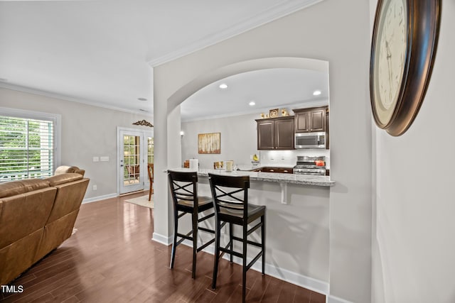 633 Copper Beech Ln, Wake Forest, NC 27587 - kitchen featuring stainless steel appliances, a breakfast bar, arched walkways, recessed lighting, and dark wood-type flooring