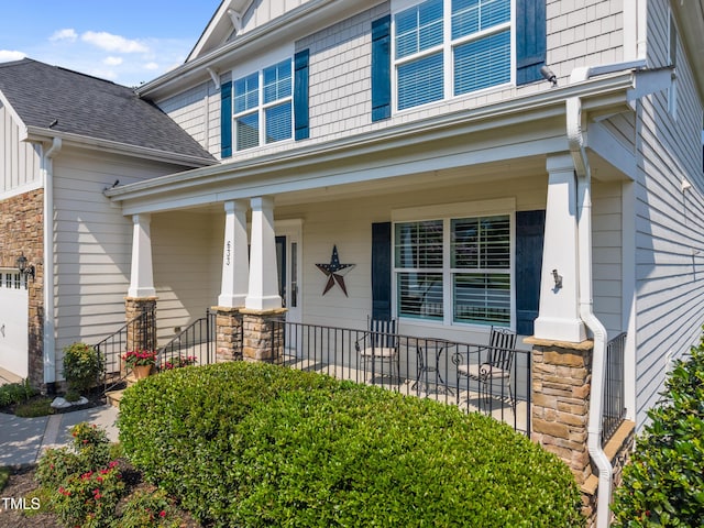 633 Copper Beech Ln, Wake Forest, NC 27587 - view of exterior entry featuring a porch, roof with shingles, stone siding, and an attached garage