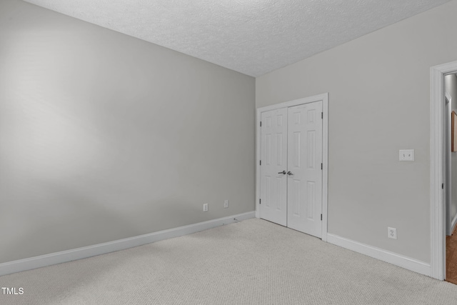 1016 Luminary Ln, Willow Springs, NC 27592 - unfurnished bedroom with carpet flooring, a closet, baseboards, and a textured ceiling