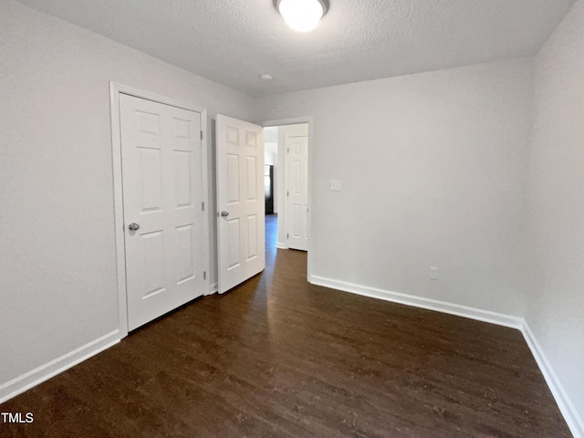 216 E Hinton St, Clayton, NC 27520 - unfurnished bedroom with baseboards, a textured ceiling, and dark wood-style flooring