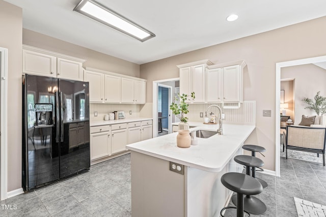 1717 Ormond Rd, Hurdle Mills, NC 27541 - kitchen with black refrigerator with ice dispenser, white cabinets, a kitchen breakfast bar, a sink, and recessed lighting