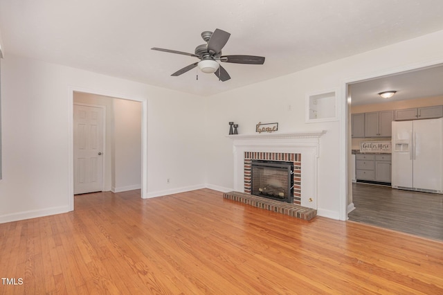 408 N Stewart St, Clayton, NC 27520 - unfurnished living room with a ceiling fan, light wood finished floors, a brick fireplace, and baseboards