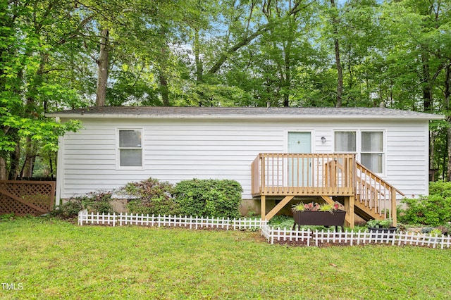 ranch-style home with a front yard, a wooden deck, and view of scattered trees