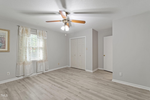 unfurnished bedroom featuring wood finished floors, baseboards, a textured ceiling, ceiling fan, and a closet