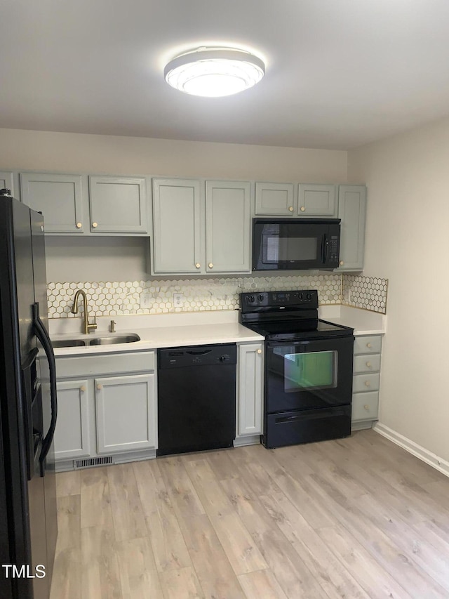 2001 Ballston Pl, Knightdale, NC 27545 - kitchen with black appliances, a sink, decorative backsplash, light countertops, and light wood-style flooring