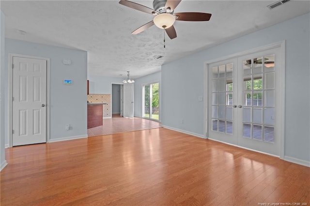11 Checkmate Ct, Cameron, NC 28326 - unfurnished living room with french doors, light wood-style flooring, a ceiling fan, a chandelier, and baseboards