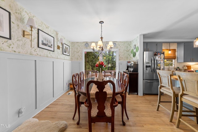 3620 Arrowwood Dr, Raleigh, NC 27604 - dining room featuring wallpapered walls, a chandelier, a wainscoted wall, light wood-style floors, and a decorative wall
