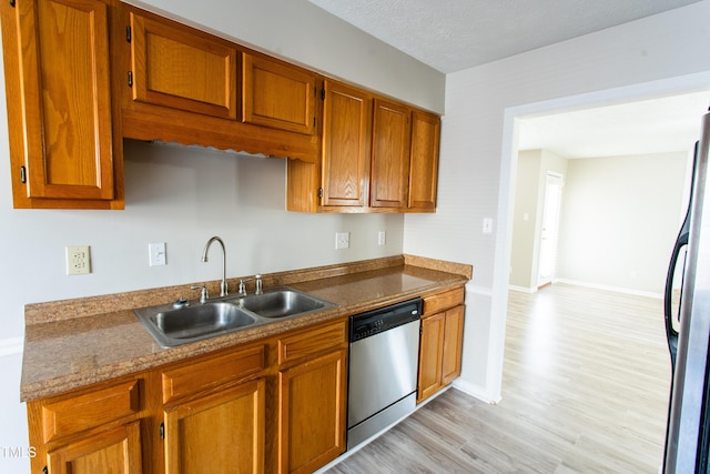 613 Sunnybrook Dr, Hope Mills, NC 28348 - kitchen featuring dishwasher, a sink, freestanding refrigerator, light wood-style floors, and brown cabinetry