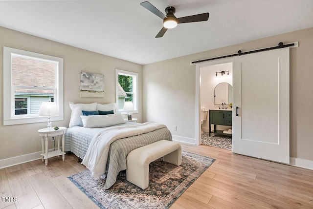 847 E Maple Ln, Fuquay Varina, NC 27526 - bedroom featuring a barn door, light wood-style floors, baseboards, and ensuite bath