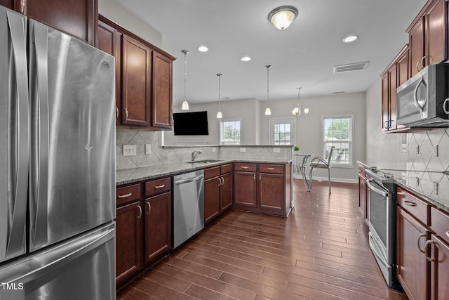 30 Sunbury Ct, Zebulon, NC 27597 - kitchen with appliances with stainless steel finishes, dark wood-style floors, dark stone counters, a peninsula, and backsplash