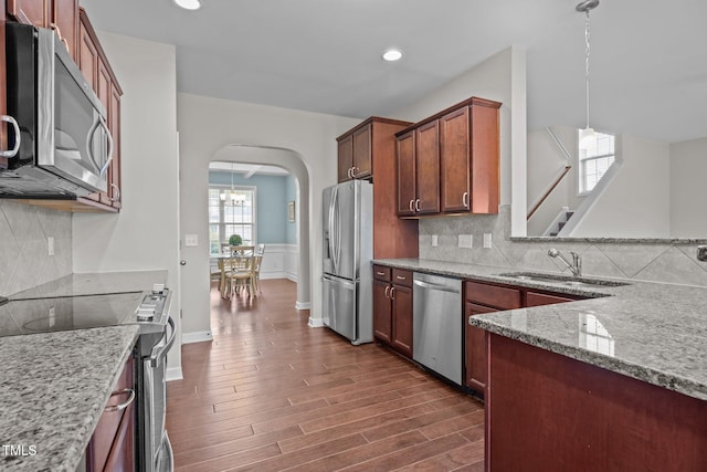 30 Sunbury Ct, Zebulon, NC 27597 - kitchen featuring appliances with stainless steel finishes, arched walkways, a sink, light stone counters, and decorative backsplash