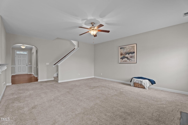 30 Sunbury Ct, Zebulon, NC 27597 - unfurnished living room with arched walkways, ceiling fan, carpet flooring, stairway, and baseboards