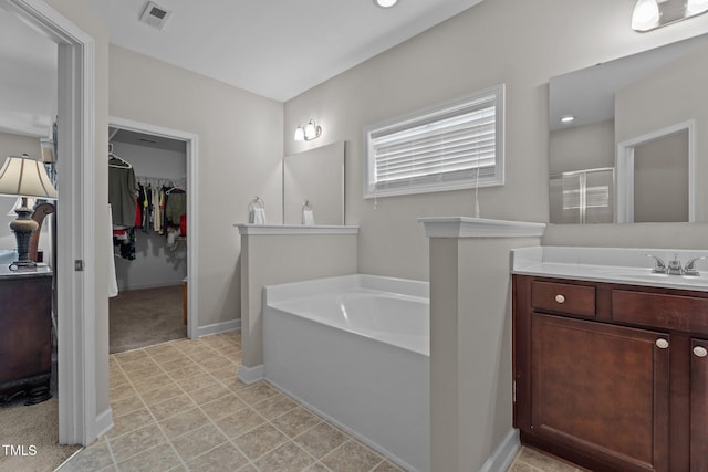 30 Sunbury Ct, Zebulon, NC 27597 - bathroom with a garden tub, a spacious closet, vanity, a stall shower, and baseboards
