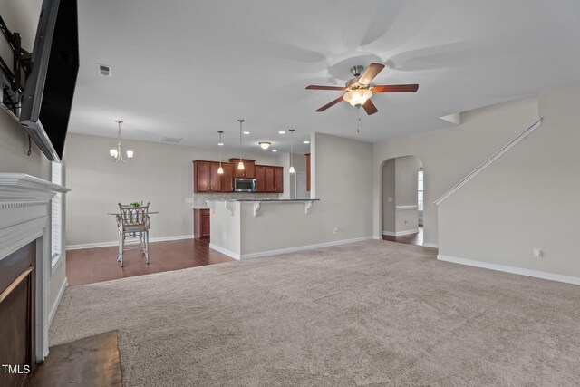 30 Sunbury Ct, Zebulon, NC 27597 - unfurnished living room featuring carpet, arched walkways, a ceiling fan, a fireplace, and baseboards