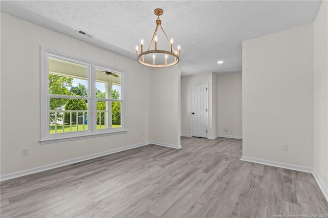 empty room with a chandelier, wood finished floors, baseboards, a textured ceiling, and recessed lighting