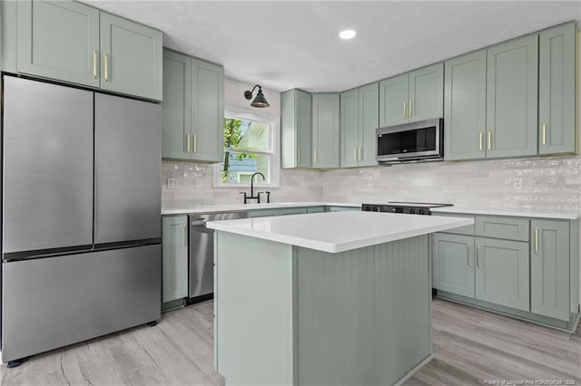 kitchen with stainless steel appliances, green cabinets, light wood finished floors, a textured ceiling, and recessed lighting