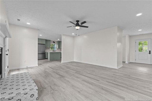 unfurnished living room featuring recessed lighting, a ceiling fan, baseboards, and light wood-type flooring